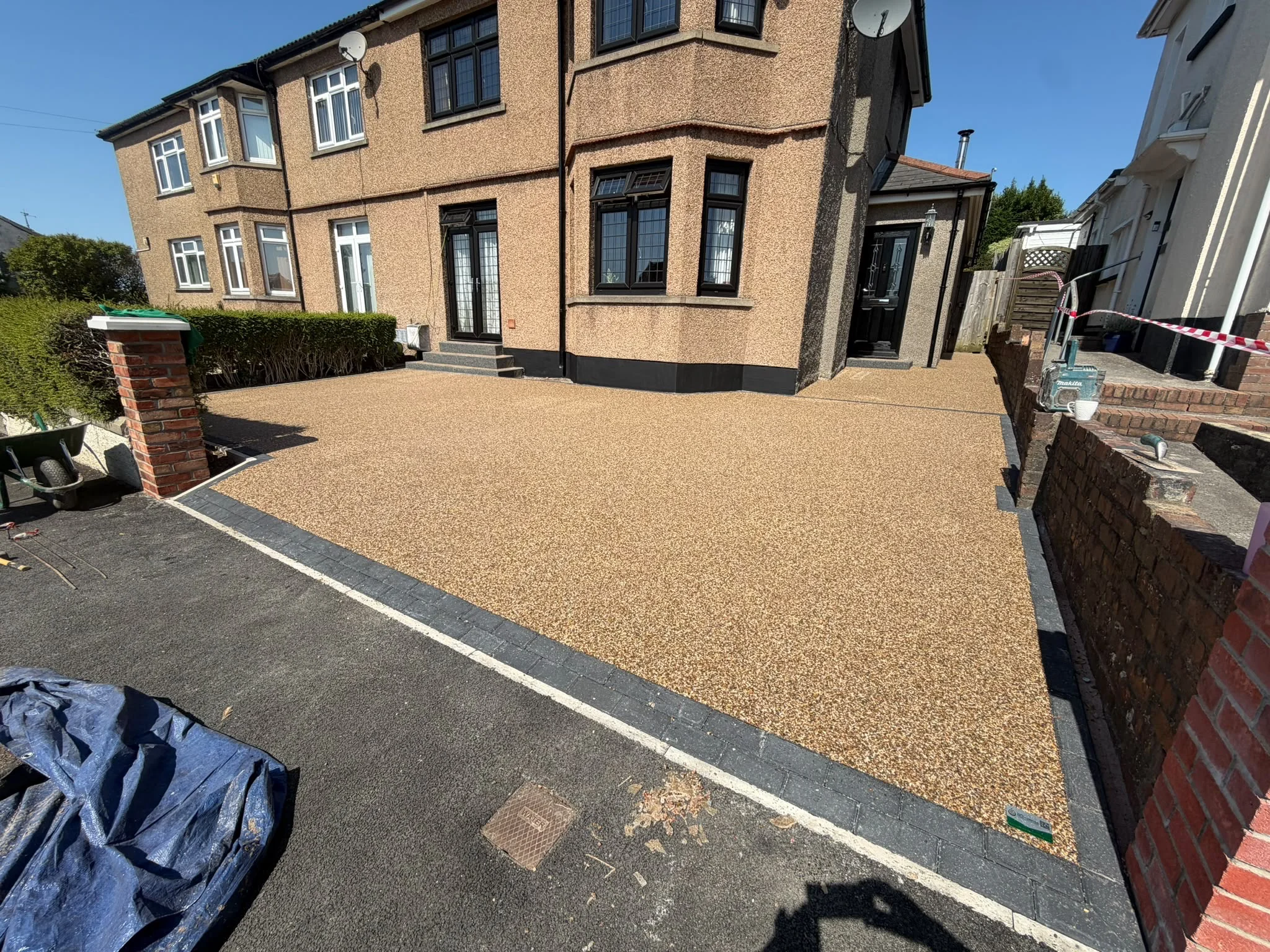 The finished Harvest Gold resin bound driveway in Bridgend, framed by a charcoal block paving border and a new capped pillar